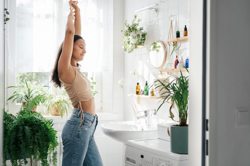 Young woman stretching in bathroom